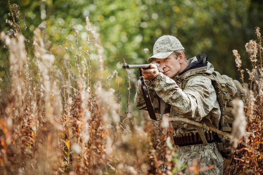 man hunter with shotgun in forest