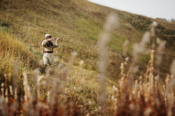 man hunter with shotgun in forest
