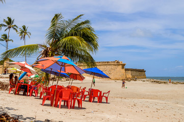 Tropical sand beach with colorful plastic chairs, tables and umb