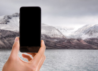 Hand holding mobile with black screen with Glacier Bay on background