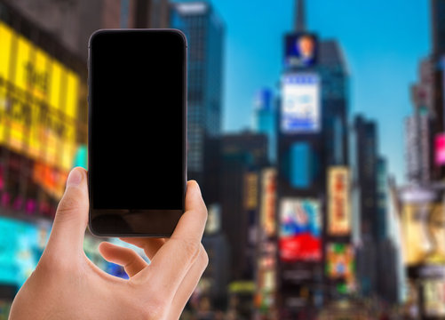 Hand holding mobile with black screen on Times Square background