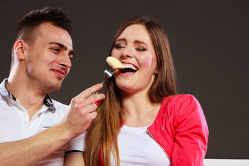 Smiling man feeding happy woman with banana.