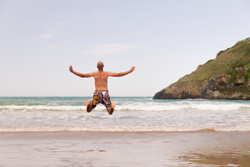 Young man jumping in the beach shore