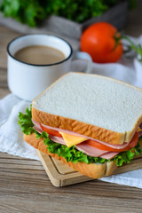 sandwich with ham, cheese and vegetables,and coffee on wood table