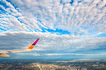 Plane wing, white clouds and blue sky