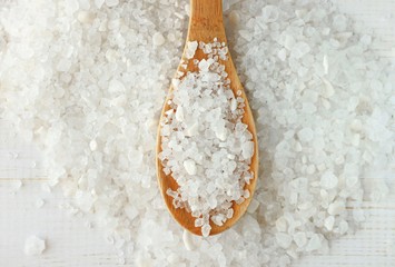 White grainy sea salt close-up, culinary and cosmetic use, wooden kitchen spoon
