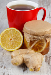 Lemon with honey, ginger and cup of tea on wooden table, healthy nutrition