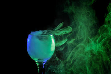 Blue and green smoke in a glass. Halloween.