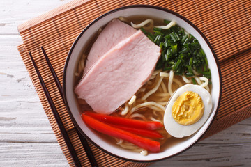 Ramen noodles in broth with pork in a bowl close up. Horizontal top view
