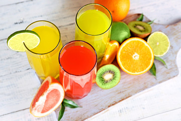 Glasses of different juice with fruits and mint on table close up