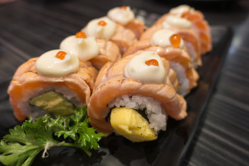 Salmon Sushi Roll with Tamagoyaki on black ceramic plate