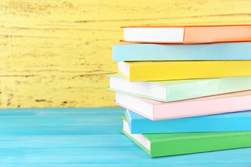 Colorful books on yellow wooden background