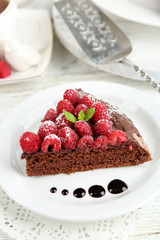 Piece of cake with chocolate Glaze and raspberries on color wooden background