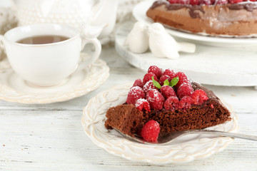 Piece of cake with chocolate Glaze and raspberries on color wooden background