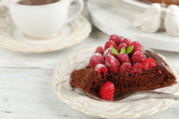 Piece of cake with chocolate Glaze and raspberries on color wooden background