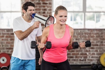 Personal trainor motivating his client with megaphone 