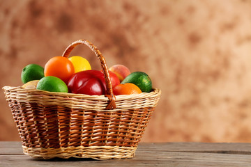 Heap of fresh fruits and vegetables in basket on wooden table close up