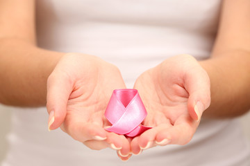 Female hands holding pink ribbon sign, closeup