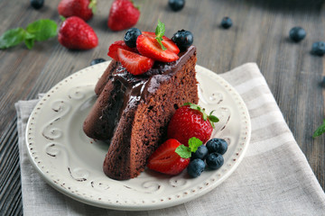 Piece of chocolate cake with berries in plate on table, closeup