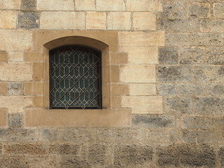 Fototapeta na wymiar One barred window at old stone wall.