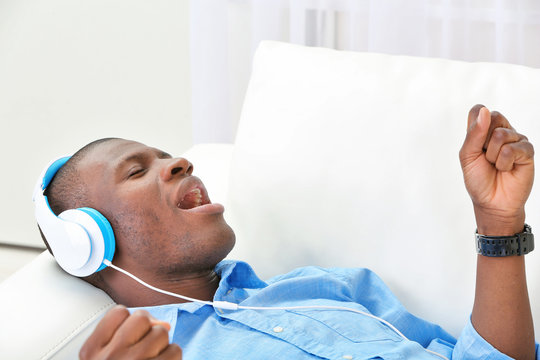 Handsome African American man with headphones lying on sofa close up