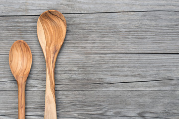 two spoons of olive wood on grey table