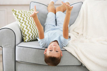 Obraz na płótnie Canvas Little boy sitting on sofa, on home interior background