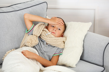 Sick boy with cold sitting on sofa