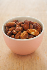 Almonds in a pink bowl on wooden