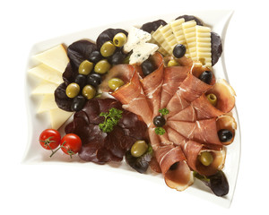 Two kinds of smoked ham and three kinds of cheese served on a white plate with olives and cherry tomatoes. Isolated on white.