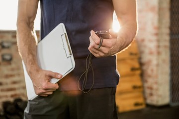 Midsection of trainer holding clipboard and stopwatch