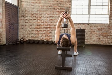 Man lifting dumbbell lying on bench