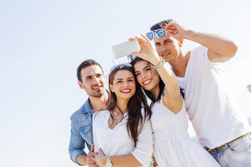 Group of cheerful and beautiful young people taking photos of th