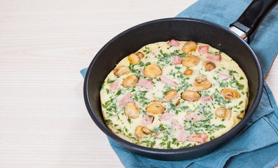 omelet with mushrooms, ham and cheese in a frying pan