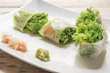 Salad roll vegetables with salad dressing in dish on wooden for