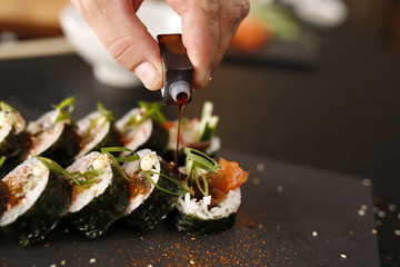 Sushi. Klasyczne  grube rolki futomaki podane na kamiennym talerzu