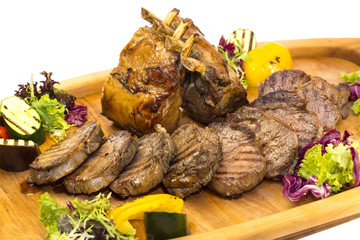 loin and steak cooked on a grill with vegetables