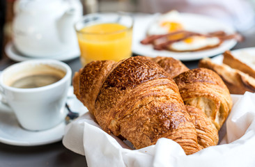 Breakfast with coffee and croissants in a basket on table