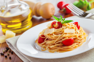 Italian spaghetti with tomato sauce, parmesan cheese and basil on table
