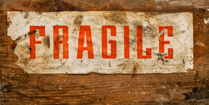 Sign with "FRAGILE" charming, old and worn, glued on a wooden board
