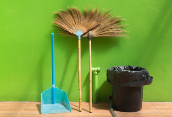 dustpan broom and bin with green wall background
