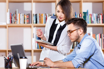 Young business woman and man looking at the laptop screen