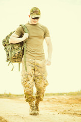 soldier walking at rural road with backpack