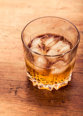 Glass of cold whiskey on wooden surface