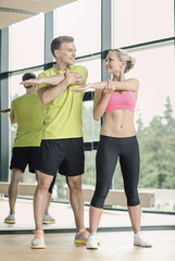 Fototapeta na wymiar smiling man and woman exercising in gym