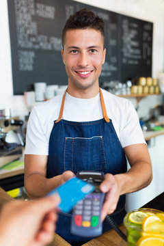Man holding credit card reader at cafe
