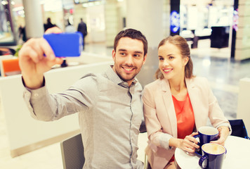 happy couple with smartphone taking selfie in mall