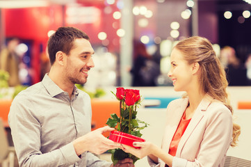 happy couple with present and flowers in mall