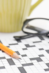 Crossword puzzle, glasses and pencil