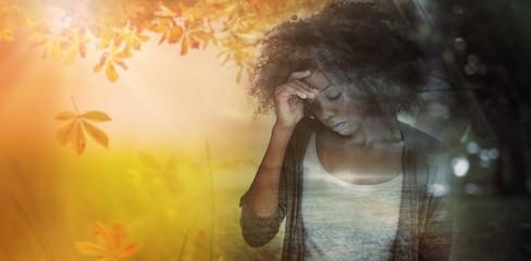 Composite image of sad woman holding her forehead with her hand